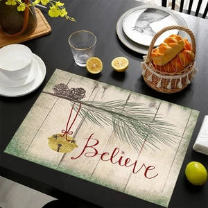 Close-up of linen Christmas placemat with pine branches, bells and 'Believe' text