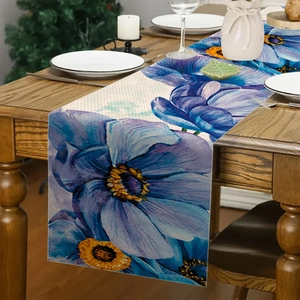 Dettaglio runner da tavola in lino con grandi fiori blu su tavolo in legno scuro