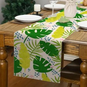 Detailopname van palm- en monstera-bladeren op een beige linnen tafelloper