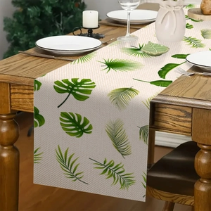 Detail van de tafelloper met tropische bladeren op een donkere houten eettafel
