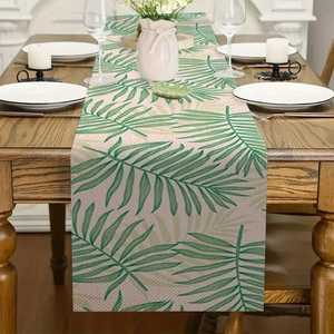 Linnen tafelloper met tropische palmbladeren op een houten tafel met decoratie