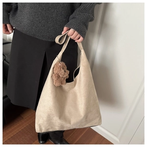 Dettaglio della grande borsa hobo in finta pelle scamosciata beige con ciondolo a orsetto