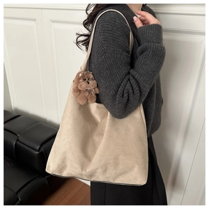 Dettaglio della borsa tote in pelle scamosciata beige con ciondolo a forma di orsetto