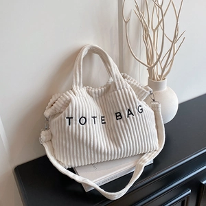 Minimalist white corduroy tote bag with black embroidery and adjustable strap