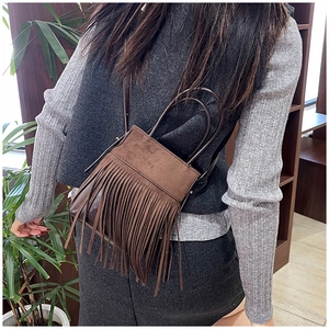 Dettaglio di una borsa tote vintage in pelle scamosciata marrone con frange su modella