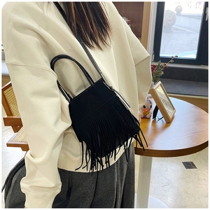 Dettaglio di una borsa a tracolla nera con lunghe frange e tracolla regolabile donna