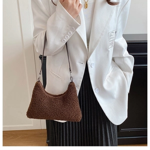 Detail of dark brown faux shearling shoulder bag with slim leather strap for autumn