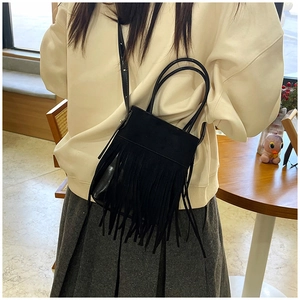 Dettaglio della frangia nera e della trama in scamosciato di una borsa a tracolla da donna