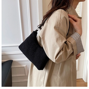 Close-up of black fuzzy plush shoulder bag with pebbled texture and sleek leather strap