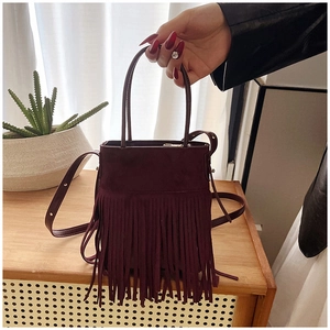 Dettaglio della borsa in pelle scamosciata bordeaux con frange e cerniera dorata