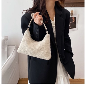 Close-up of white plush shoulder bag with leather strap worn by a fashion model
