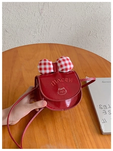 Detail of red glossy crossbody bag with plaid bow and cute cat embroidery for children