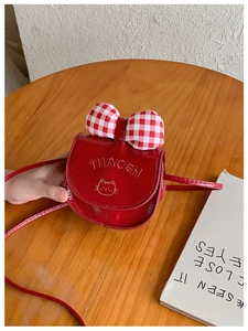 Detail of red kids crossbody bag with a large red checkered bow and cute cat embroidery