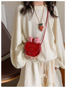 Detail of red kids crossbody bag featuring a plaid bow and cute cat face texture