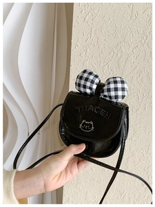 Detail of cute cat pattern and plaid bow on children's black glossy crossbody bag