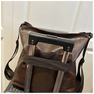 Dettaglio borsa tote marrone scuro con fascia per valigia e trama in pelle cerata