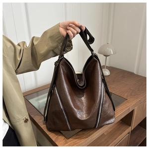 Dettaglio della borsa tote in pelle marrone scuro con finitura lucida e cerniere argento