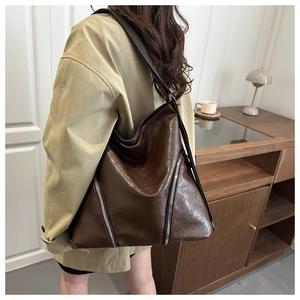 Dettaglio di una grande borsa tote marrone scuro in pelle PU lucida con cerniere silver