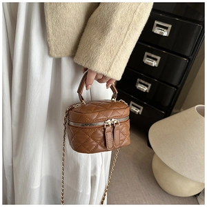 Detail of a brown quilted mini box bag with gold chain and double zipper closure