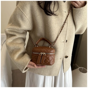 Detailed macro of brown quilted vanity bag featuring gold dual zipper and chain strap