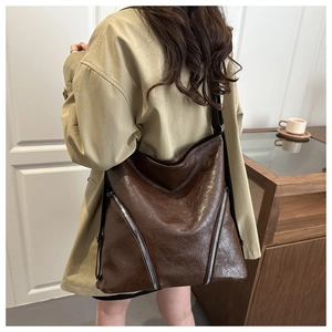 Dettaglio di una borsa tote grande marrone scuro con cerniere decorative argento