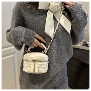 Close-up of white quilted mini vanity bag with gold chain and dual zipper detail