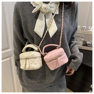 Detail of mini quilted vanity bag with metal chain strap and top handle in white and pink