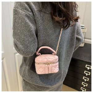 Detail of pink quilted mini bag with gold chain strap on grey knit sweater background