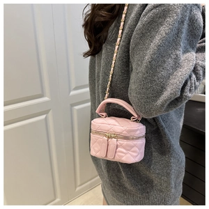 Detail of pink quilted mini box bag with gold chain strap on grey sweater