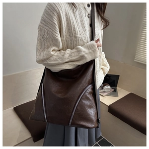 Dettaglio della grande borsa tote marrone caffè in pelle testurizzata con zip diagonali