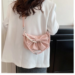 Dettaglio della borsa rosa con fiocco, catena di perle e texture in PU sul modello