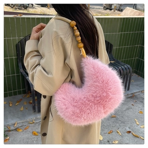 Sac croissant en peluche rose avec bandoulière en perles de bois sur un manteau