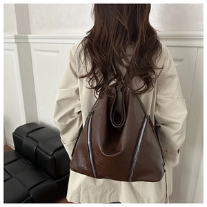 Dettaglio della grande borsa tote marrone scuro con cerniere in metallo e texture in pelle