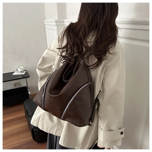 Dettaglio della texture in pelle marrone scuro e cerniera argentata della borsa