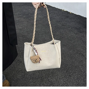 Dettaglio della borsa tote bianco off-white con manici intrecciati e ciondolo a orsetto