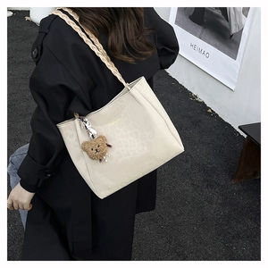 Dettaglio della borsa tote crema con stampa leopardata, testo Creative Cat e ciondolo orso