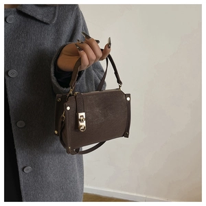 Dettaglio borsa vintage in pelle marrone con chiusura in metallo dorato e borchie
