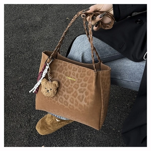Dettaglio della borsa tote leopardata con ciondolo a orsetto e logo Creative Cat