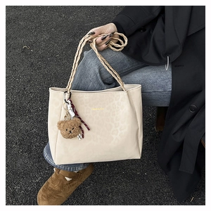 Dettaglio della borsa tote leopardata beige con manico in corda e ciondolo a orsetto