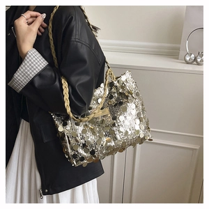 Dettaglio di grandi paillettes e tracolla intrecciata color crema di una borsa moda