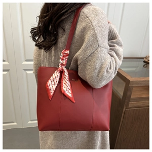 Dettaglio della borsa tote in pelle opaca rossa con sciarpa di seta sul manico
