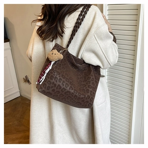 Dettaglio borsa tote leopardata con manici intrecciati e ciondolo orso su cappotto beige