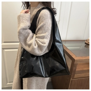 Borsa hobo nera lucida di grande capacità mostrata di lato su una modella