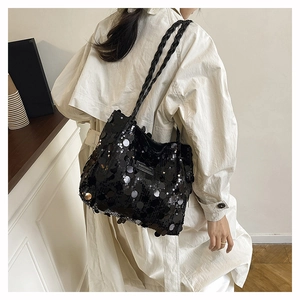 Dettaglio della borsa tote con paillettes nere e tracolla intrecciata indossata da modella