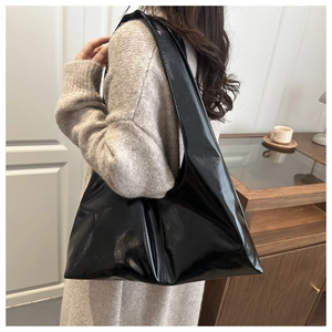 Modella che indossa una grande borsa a spalla in pelle lucida nera per lo stile casual