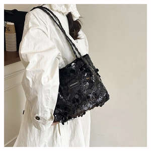 Dettaglio di una grande borsa tote con paillettes nere riflettenti e etichetta moda