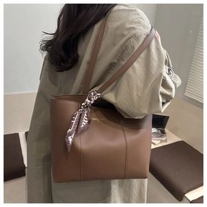 Dettaglio della borsa tote in pelle marrone scuro con foulard in seta e logo dorato