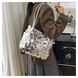 Dettaglio di paillettes argentate e tracolla intrecciata su una borsa a spalla chic