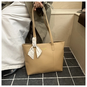 Dettaglio della borsa tote beige minimalista con foulard e logo dorato elegante