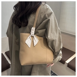 Dettaglio della borsa tote kaki con elegante foulard di seta legato al manico